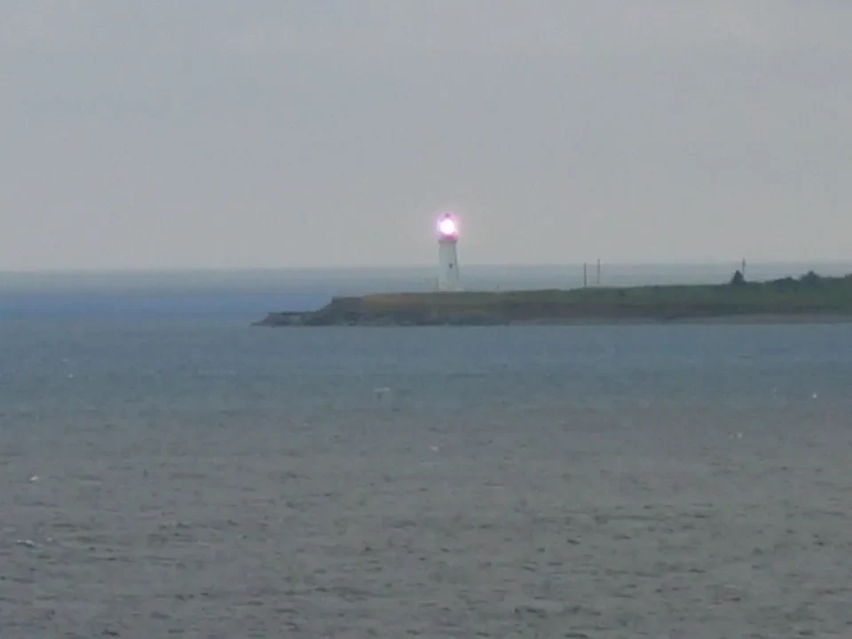 Un faro si erge su una piccola isola rocciosa nell'acqua.