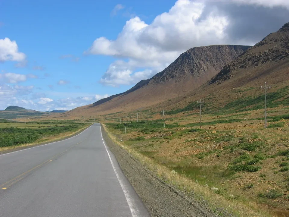 Una strada asfaltata attraversa un paesaggio rurale e collinare in Canada orientale.