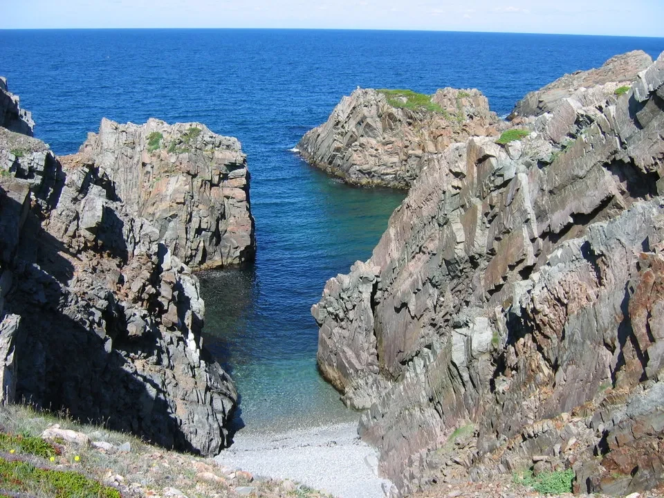 Falesie rocciose e acque cristalline formano una baia costiera.