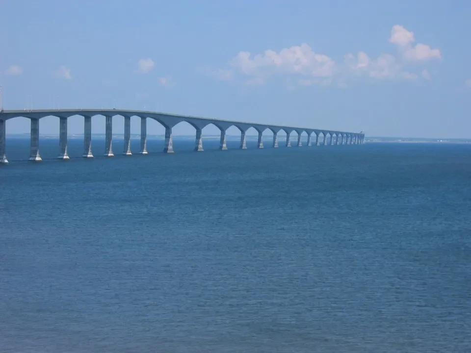 Un lungo ponte si estende attraverso l'acqua blu sotto un cielo parzialmente nuvoloso.
