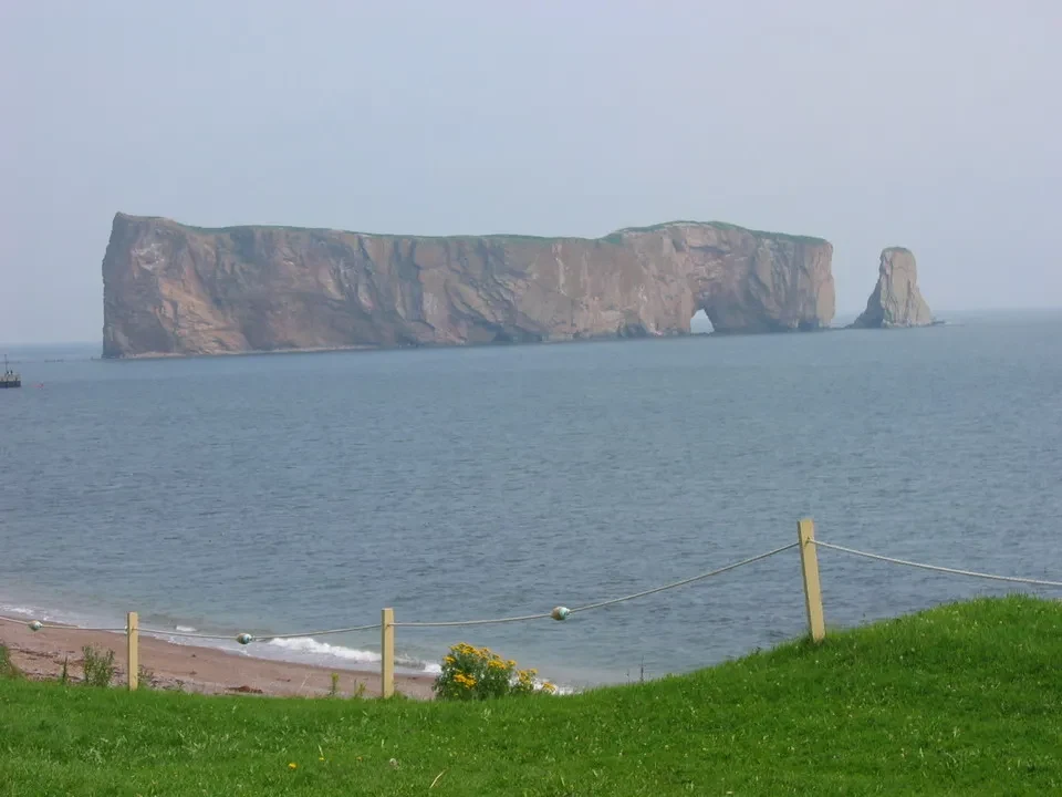 Una formazione rocciosa di terra si protende nell'acqua con un'altra isola più piccola visibile in lontananza.