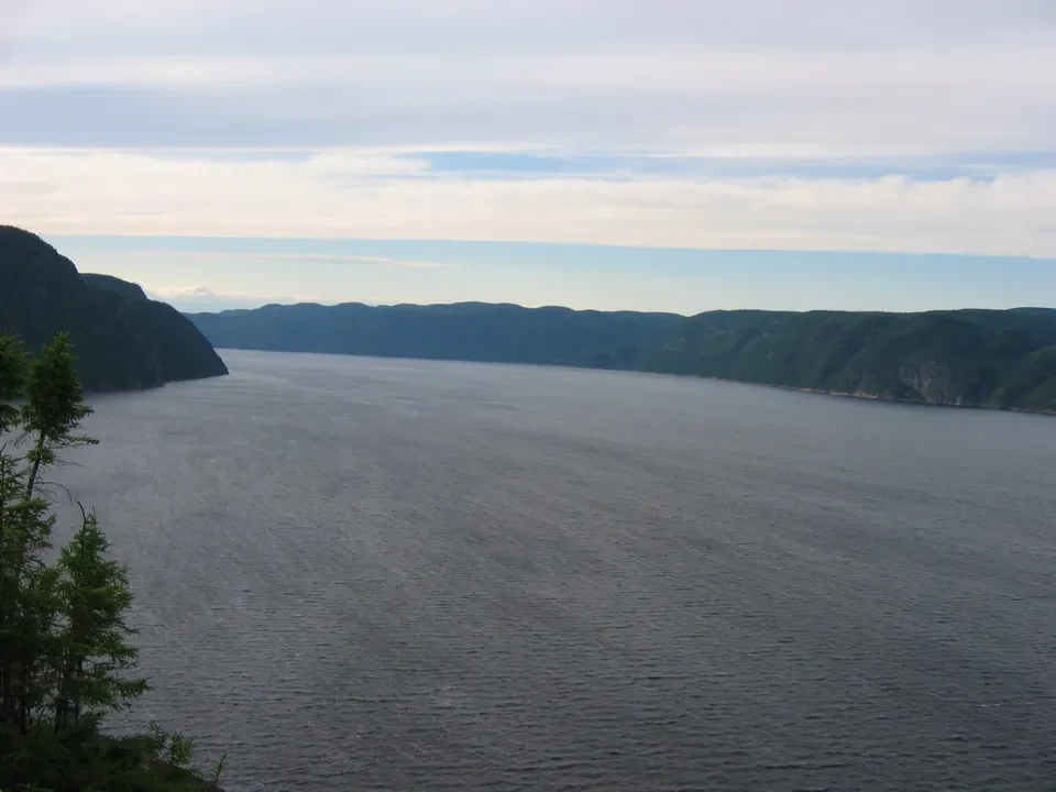 Paesaggio panoramico di un lago incorniciato da colline boscose e montagne in Canada orientale.