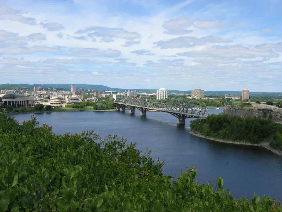 Un ponte attraversa un fiume con una città visibile in Canada Orientale.
