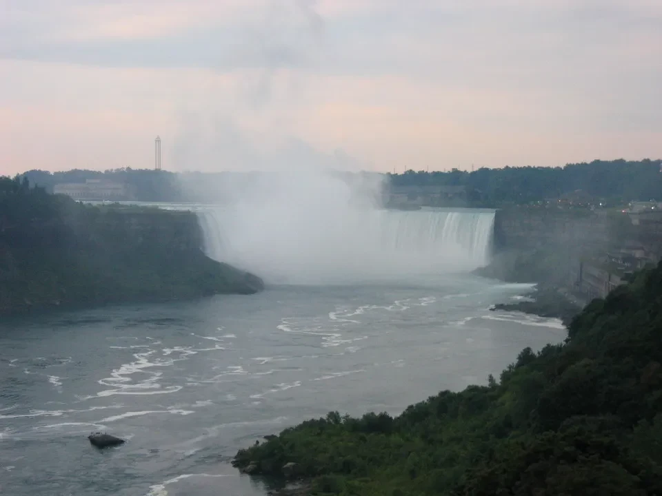 Cascata imponente con nebbia che avvolge il fiume in un paesaggio verdeggiante.