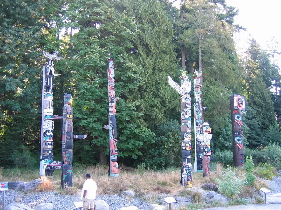Pali totem si trovano in un'area erbosa e boscosa.