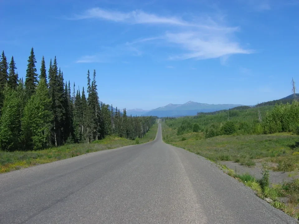 Una strada asfaltata si estende attraverso un paesaggio boscoso in Canada Occidentale.