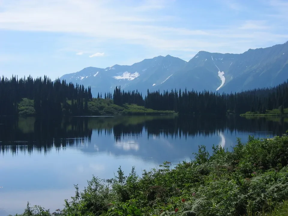 Paesaggio alpino con un lago riflesso e foreste boscose in Canada Occidentale.