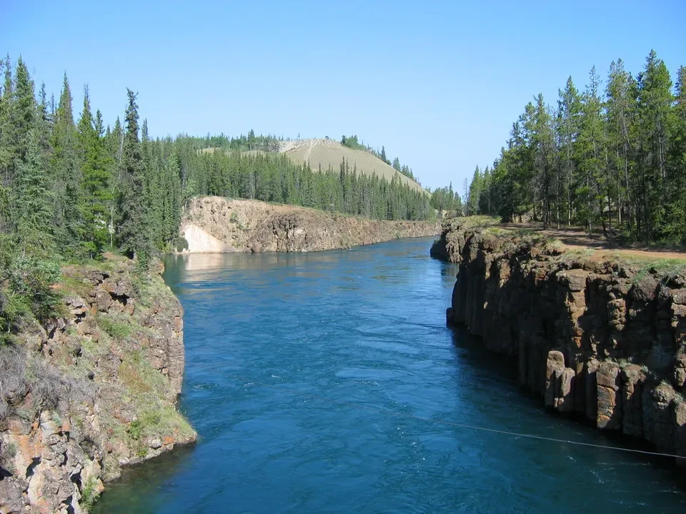 Paesaggio fluviale con pareti rocciose e foreste lungo il fiume in Canada Occidentale.