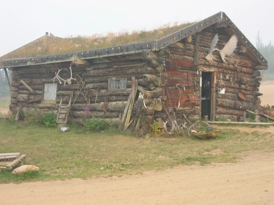 Una vecchia stalla in legno con decorazioni rustiche si trova in un paesaggio rurale.