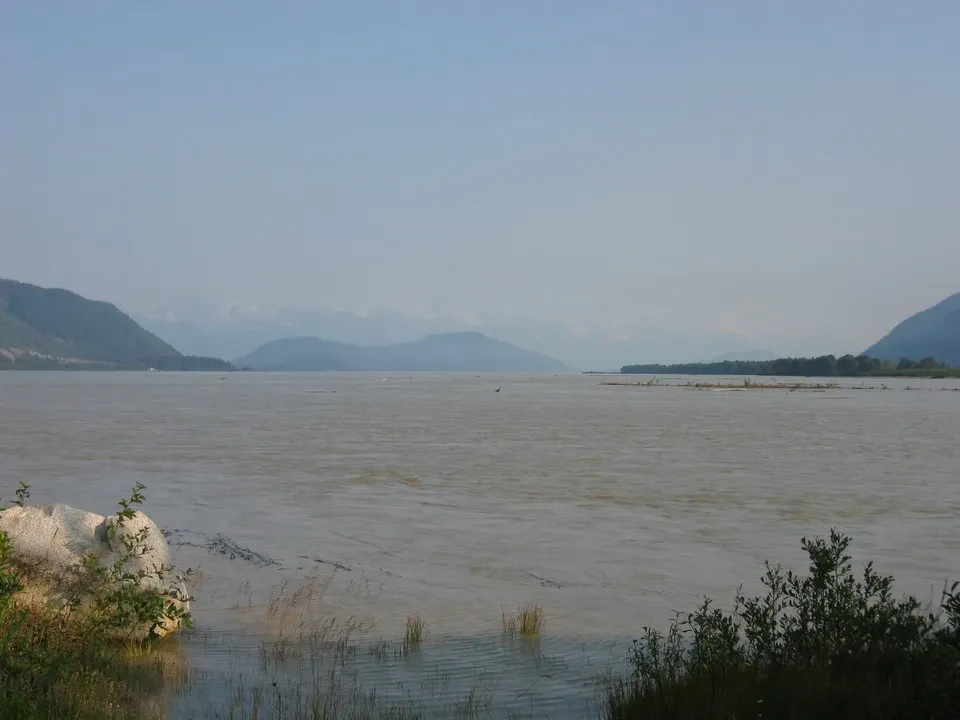 Paesaggio fluviale ampio con montagne sullo sfondo in Canada Occidentale.