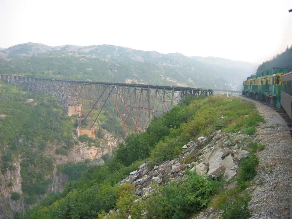 Una ferrovia in legno attraversa un paesaggio montano nebbioso in Canada Occidentale.