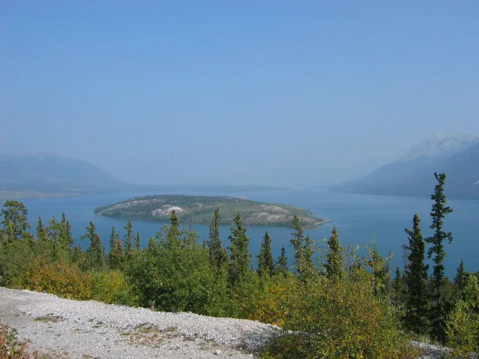 Vista panoramica di un lago circondato da montagne e foreste.