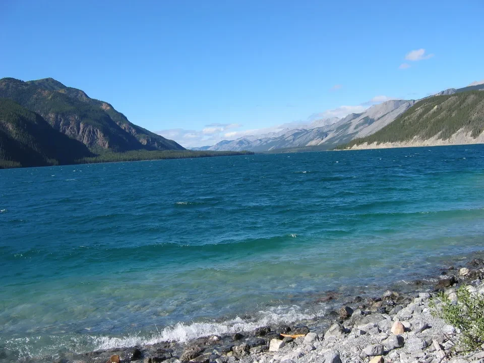 Acqua turchese di un lago circondato da montagne boscose.