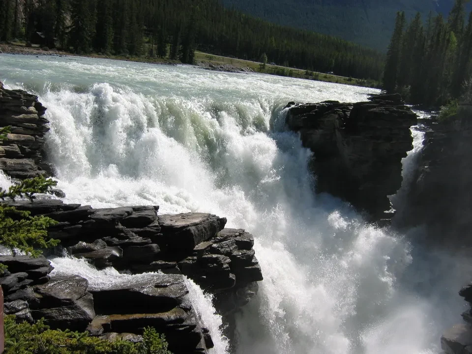 Una cascata imponente scorre tra rocce scure nella natura selvaggia del Canada occidentale.