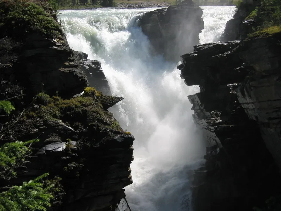 Cascata imponente scorre tra le rocce boscose.