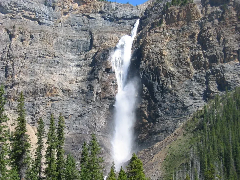 Cascata imponente scorre lungo una parete rocciosa nel paesaggio selvaggio del Canada occidentale.